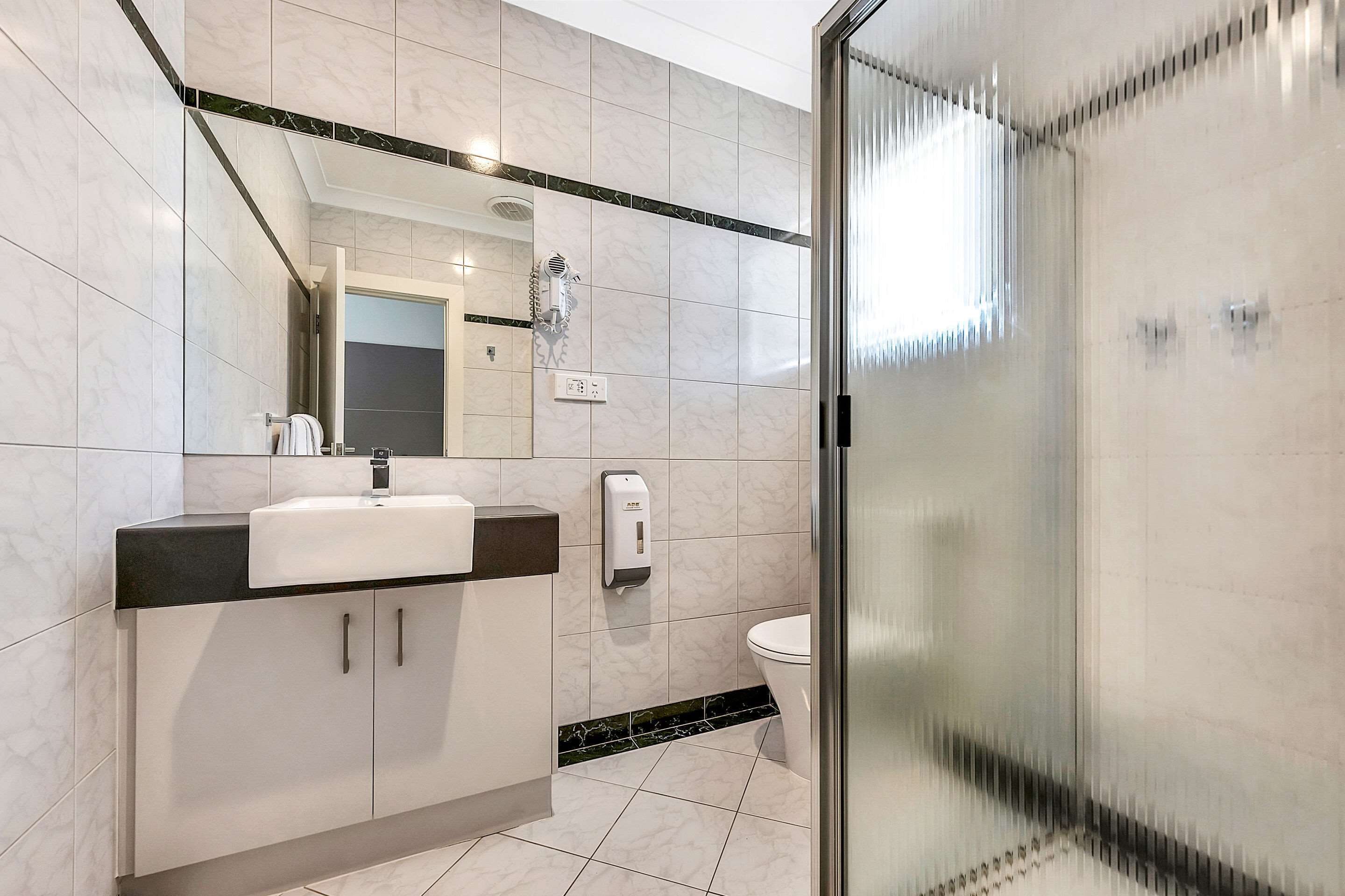A modern bathroom with a sink, mirror, and toilet.