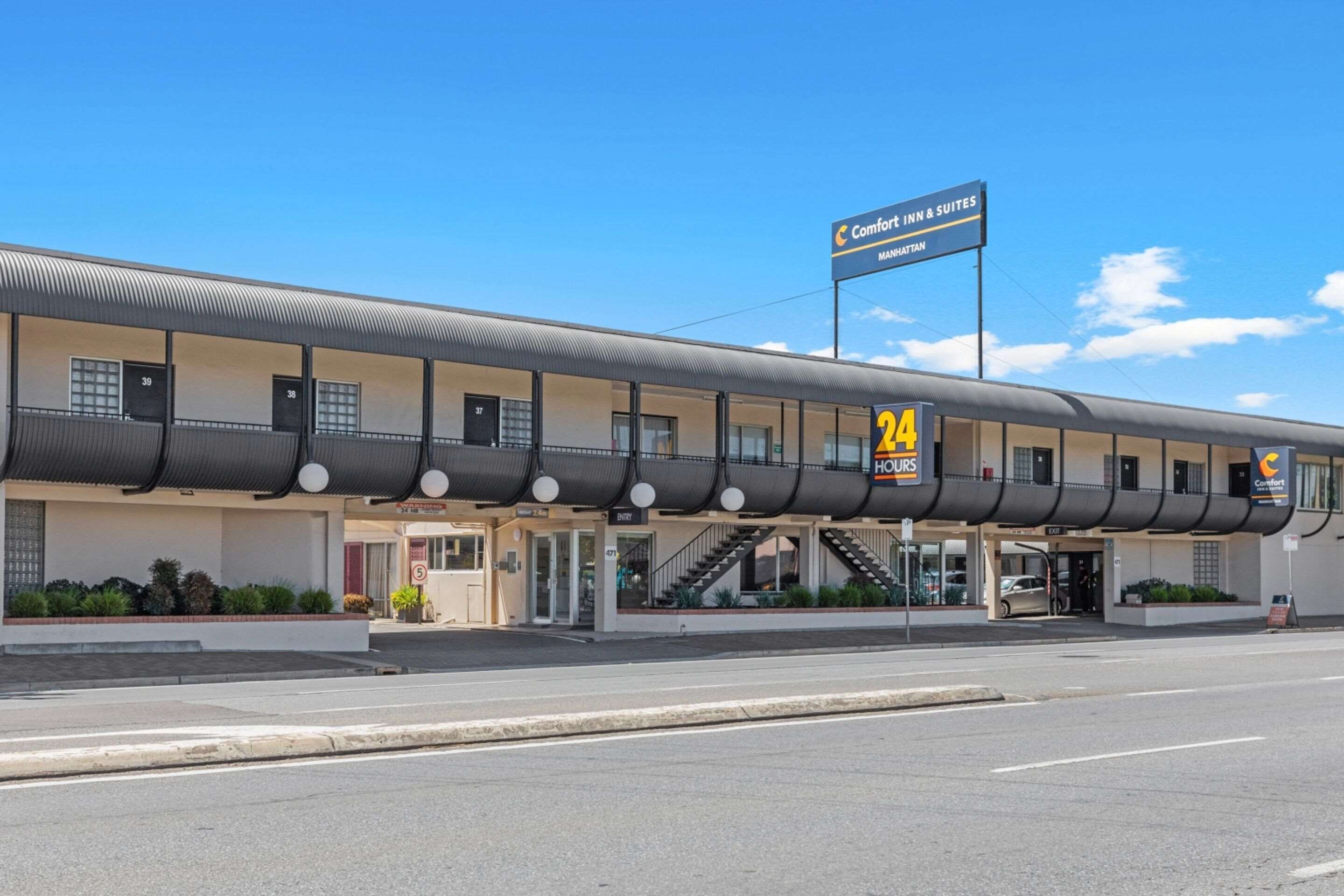 Un motel con servicio las 24 horas, un cartel que indica 'Comfort Inn & Suites' en Manhattan y un estacionamiento.