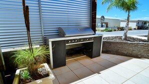 Ein Außenbereich mit Küche, Grill, Blumentöpfen und Blick auf eine Wohnstraße.