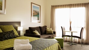 Ein Hotelzimmer mit einem Bett, einer Couch, einem Tisch mit Stühlen und einem Fenster mit Vorhängen.