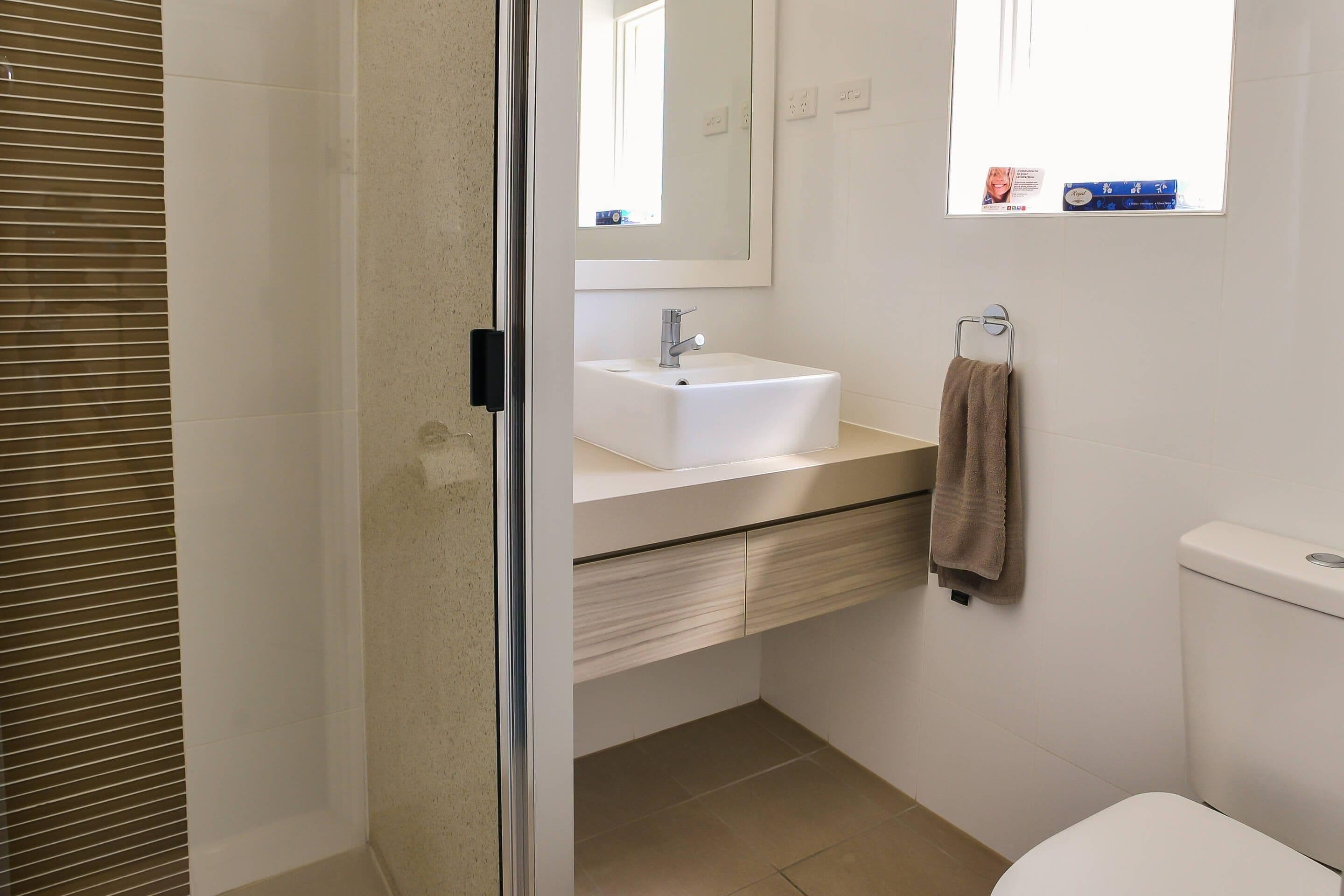A bathroom with a white sink, a mirror, a towel rack, and a toilet.