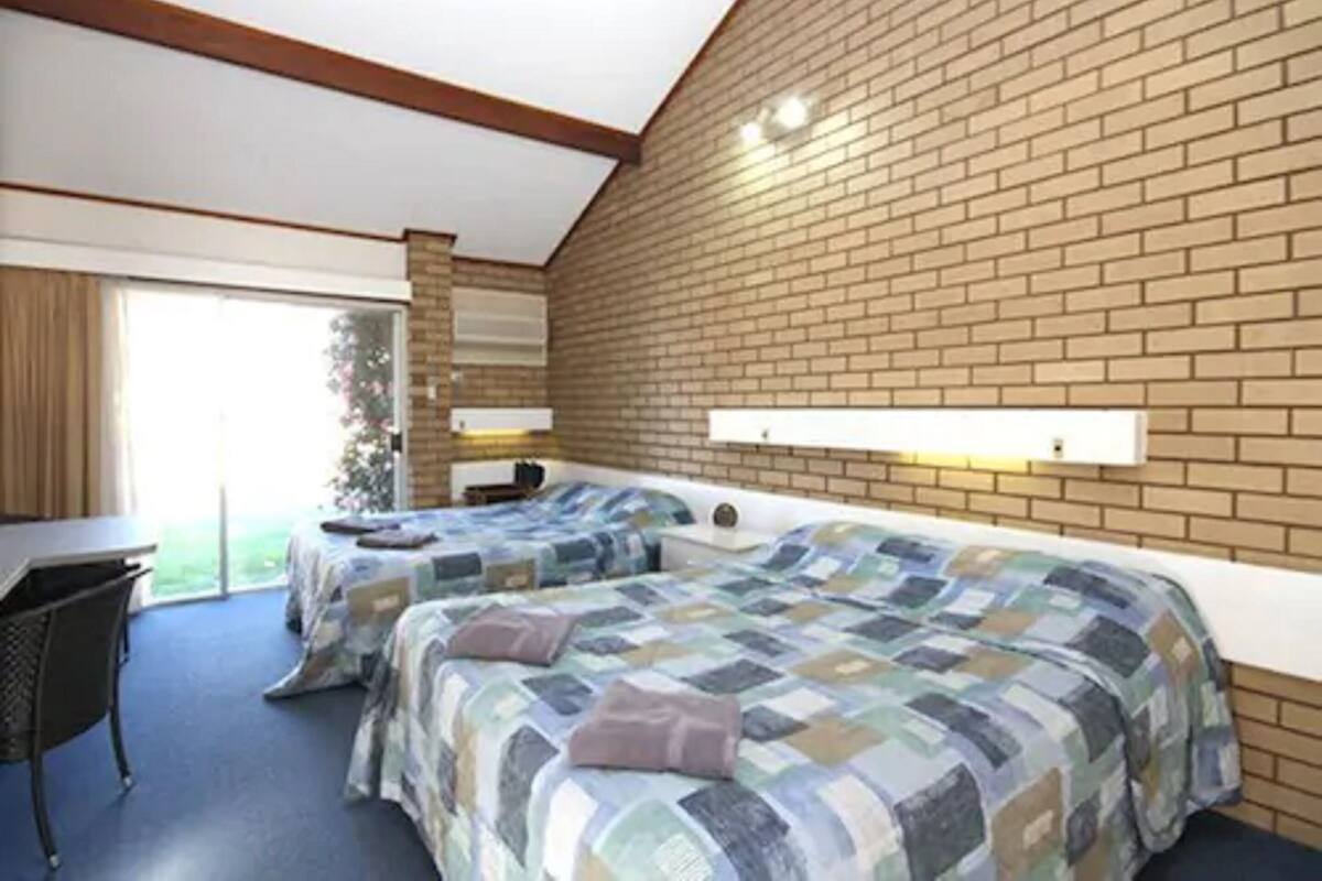 Ein Hotelzimmer mit zwei Betten, einem Schreibtisch und einem großen Fenster.