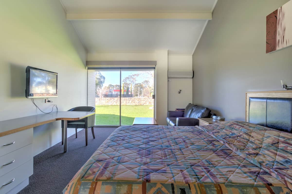 Ein Schlafzimmer mit Bett, Schreibtisch, Stuhl und Fernseher.