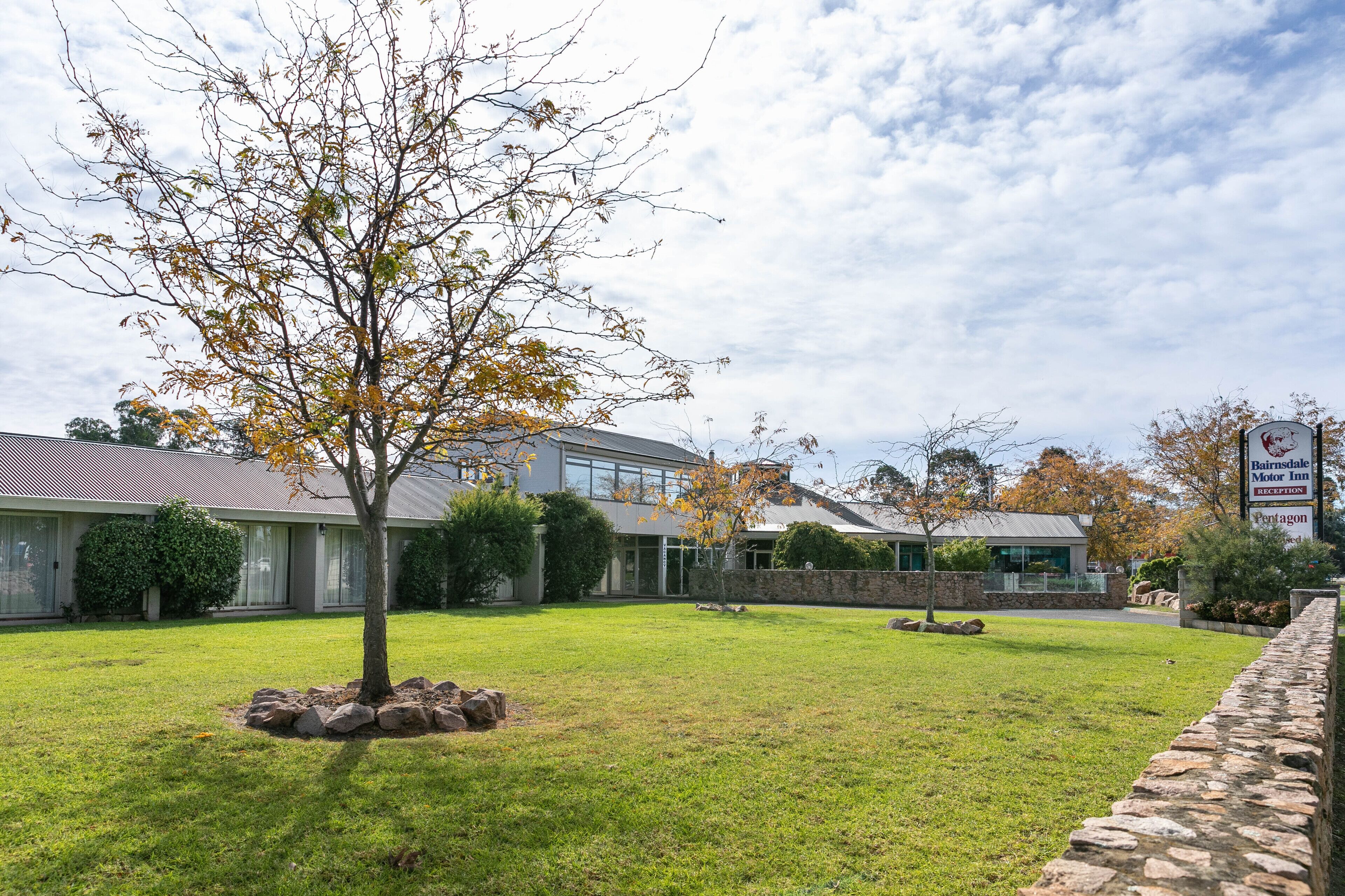 A modern building with a well-maintained lawn and a stone wall.