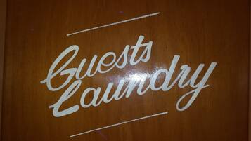 A wooden sign with the words "Guests Laundry" written in white cursive letters.
