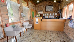 Una habitación acogedora con una mesa de recepción, dos sillas, un extintor y un suelo estampado.