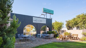 Un edificio con un letrero que dice "Colac Mid City Motel and Suites", con asientos exteriores y un patio de piedra.