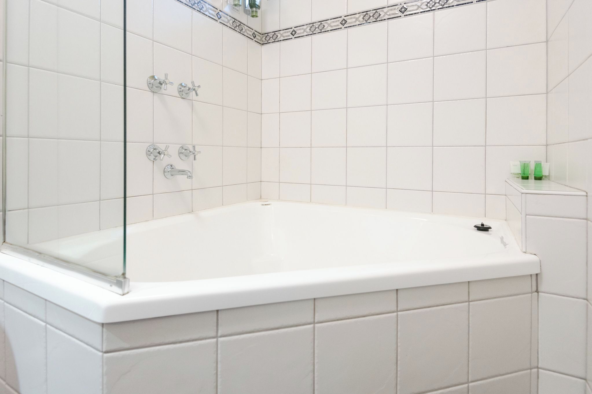 Een moderne badkamer met een vrijstaand bad, witte betegelde wanden en een glazen douchecabine.