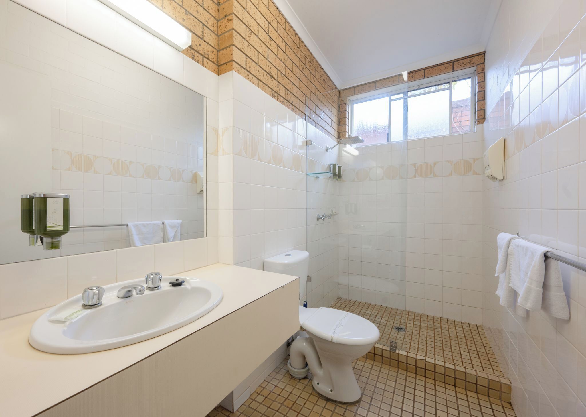 A modern bathroom with a white sink, toilet, and shower.