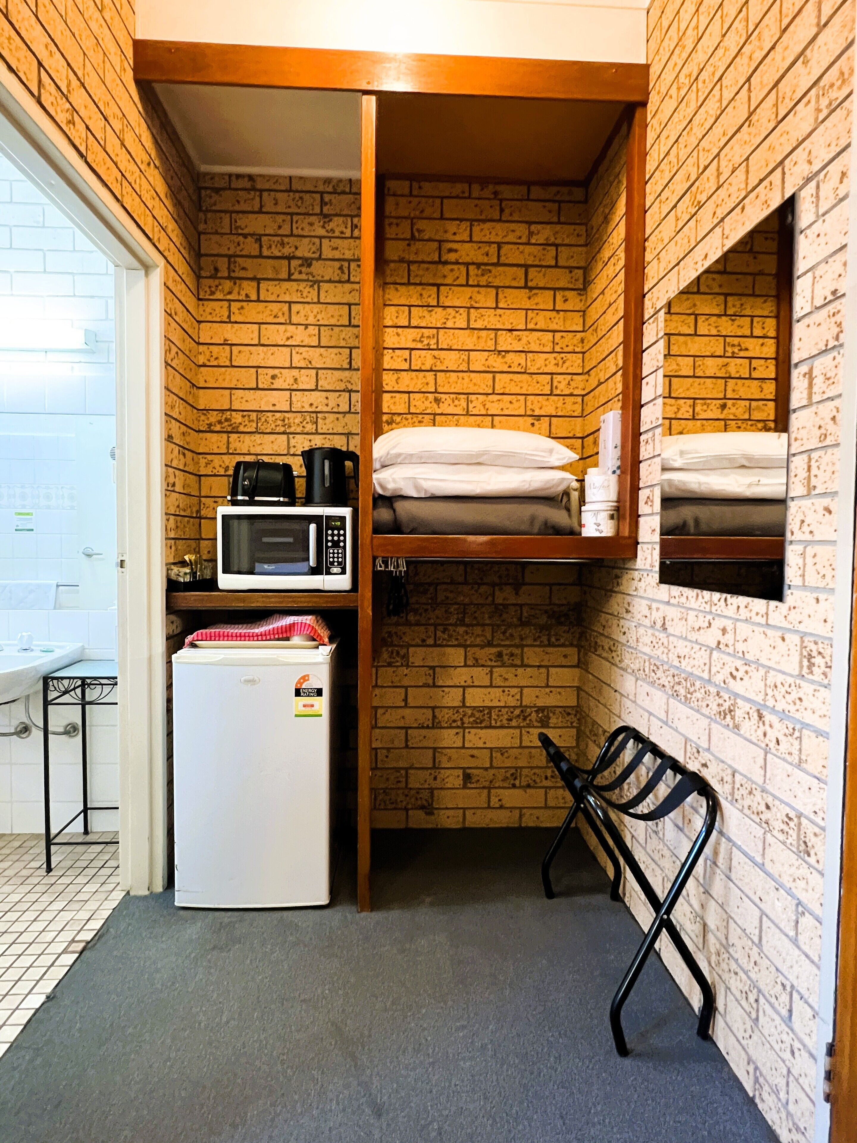 A compact room with a kitchenette, a bed, and a small seating area.