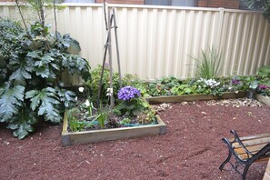 A garden with raised beds, a wooden bench, and a fence.