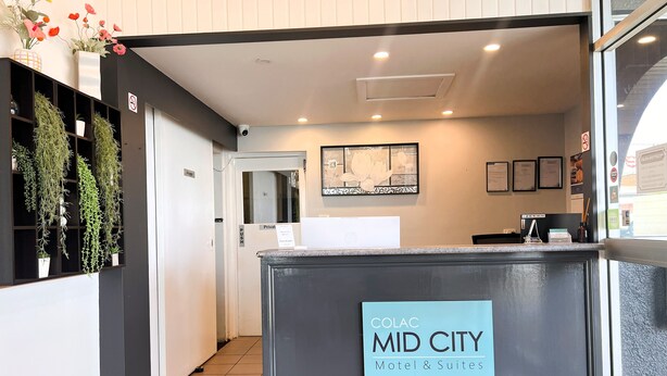 Una recepción con un letrero que dice "COLAC MID CITY Motel & Suites".