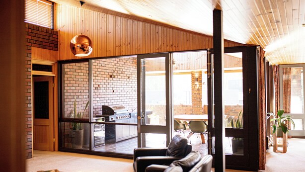 A modern interior with a brick fireplace, sliding glass doors to an outdoor patio, and a cozy seating area. - Echuca Nirebo Motel (Echuca)