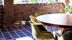 A room with a wooden ceiling, a brick wall, a large window, and a round table with chairs. - Echuca Nirebo Motel (Echuca)