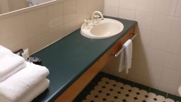 A bathroom with a sink, mirror, and a tiled floor with a hexagonal pattern.