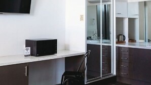 A modern hotel room with a flat-screen TV, a desk, a chair, a large mirror, and a sliding glass door leading to a bathroom. - Echuca Nirebo Motel (Echuca)