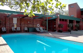 Piscina con sillas de descanso y un área de estar cubierta.