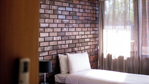 A hotel room with two beds, a brick-patterned wall, a ceiling light, and sheer curtains. - Echuca Nirebo Motel (Echuca)