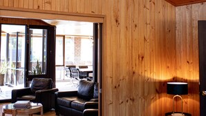 A modern interior with wooden panel walls, a large round light fixture, a leather sofa, and a dining area visible through an open door. - Echuca Nirebo Motel (Echuca)