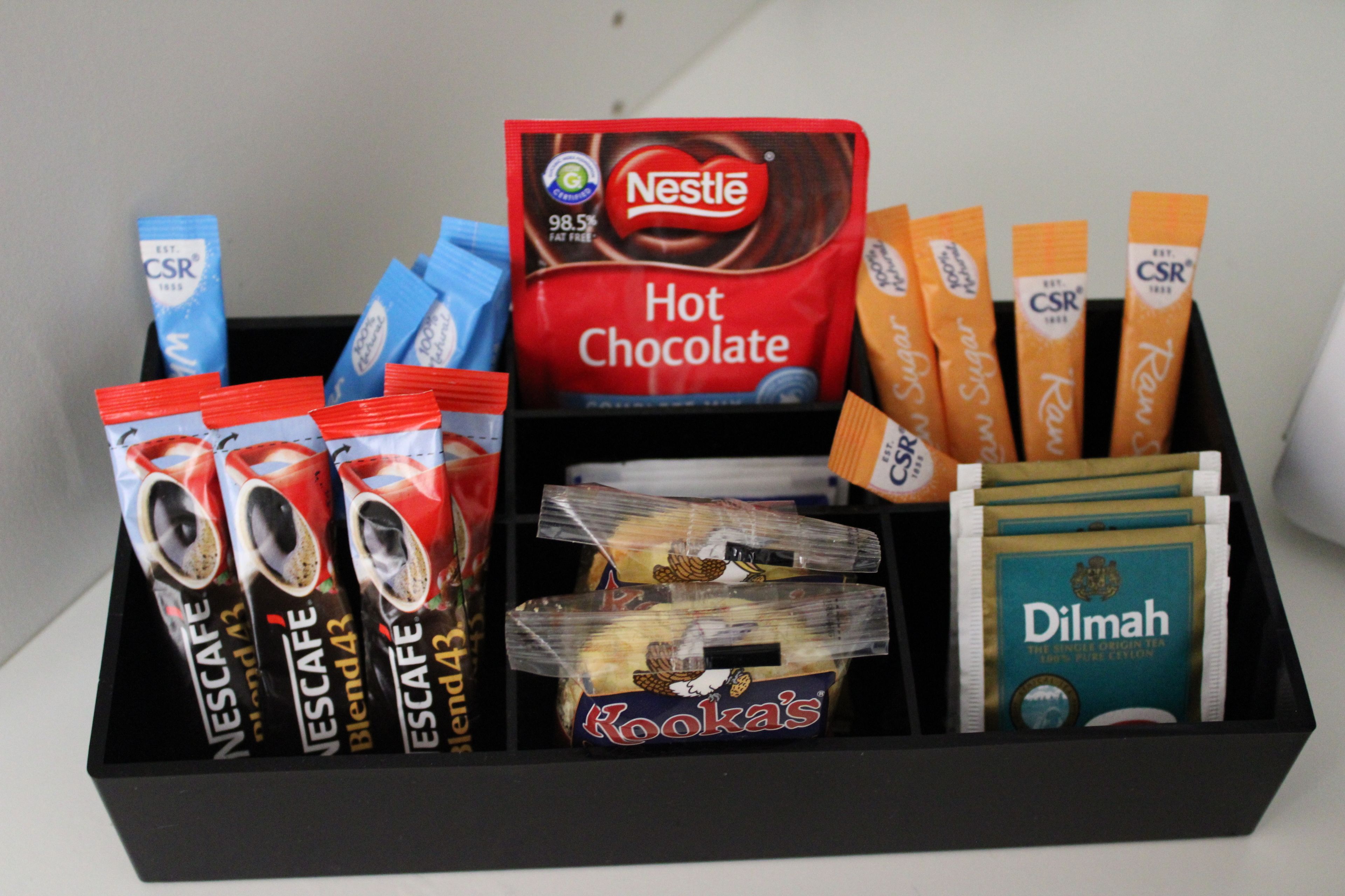 A box containing various coffee and tea products including Nestle Hot Chocolate, Kook's, and Dilmah.