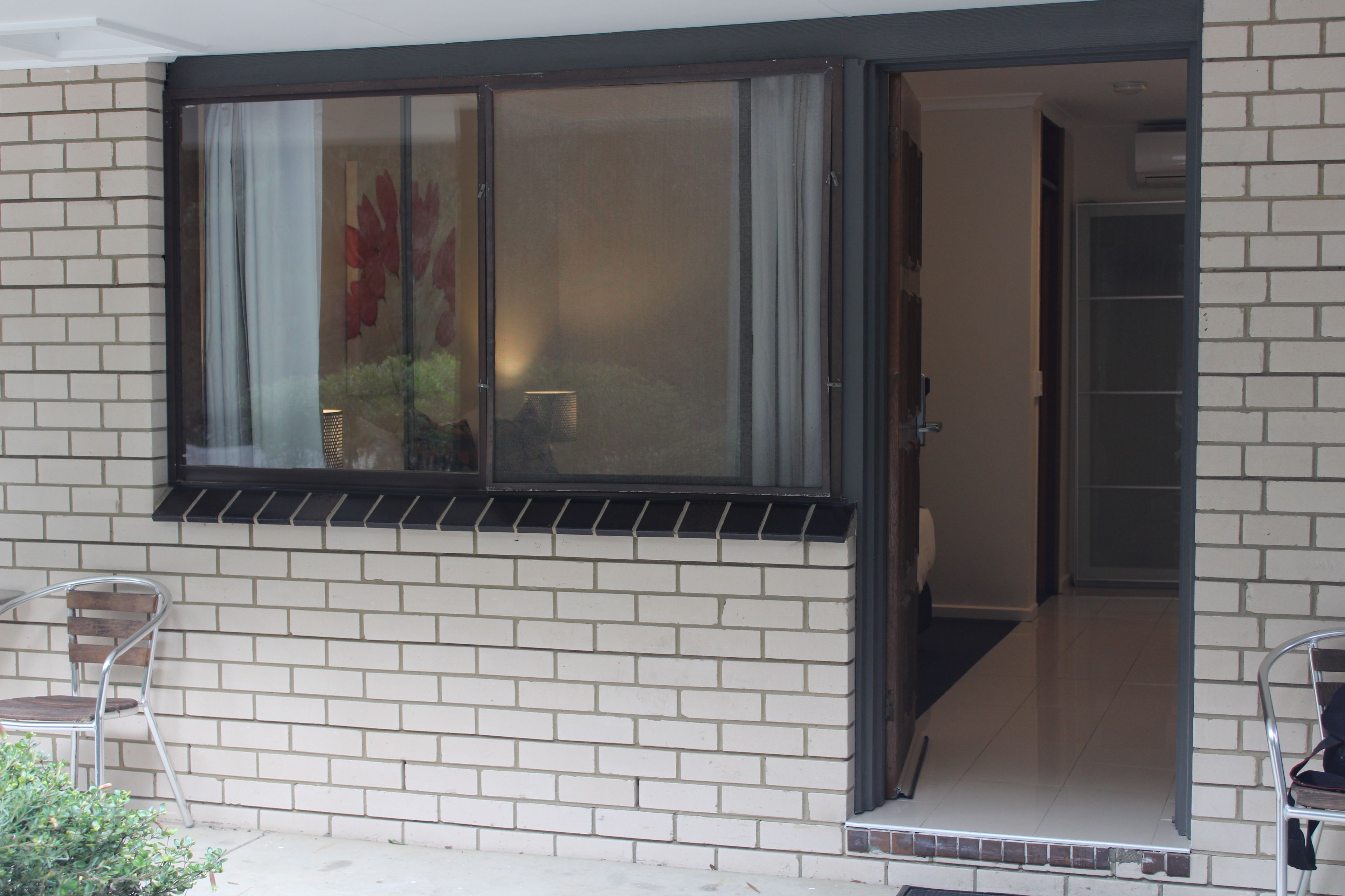 A room with a large window, a door, and a small balcony area.