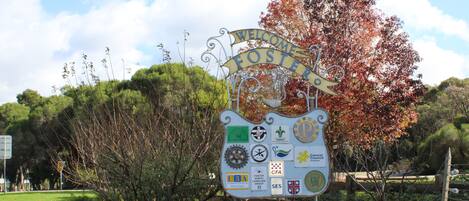 Un letrero de bienvenida con varios logotipos y un jardín.