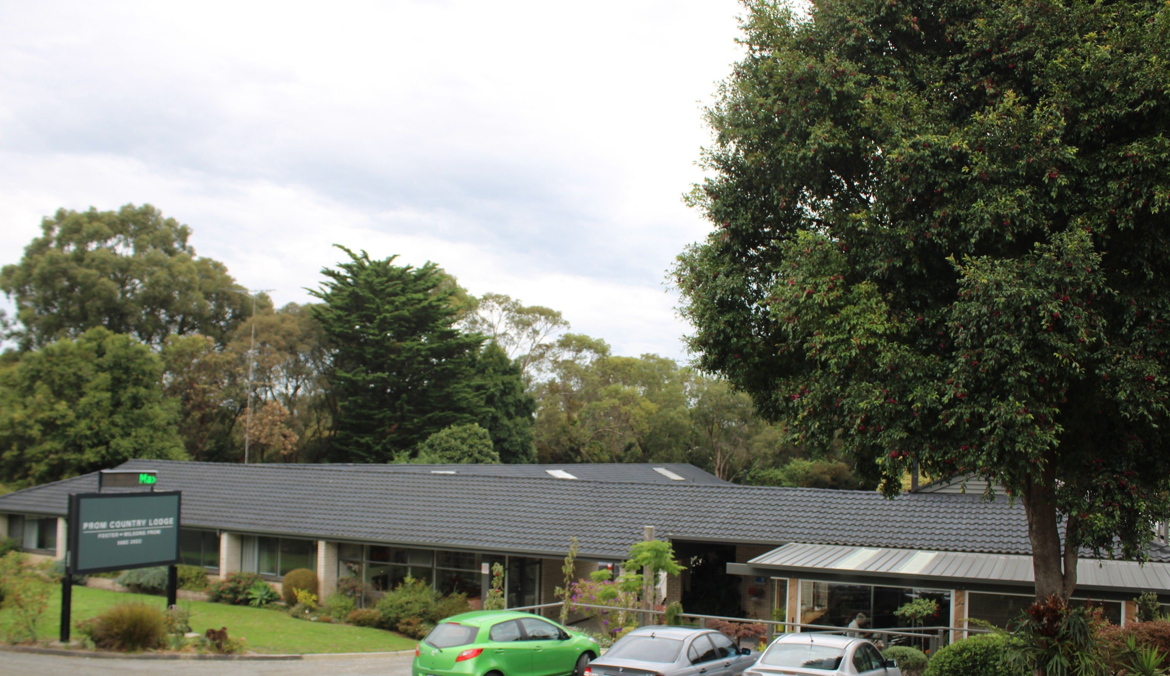 A building with a sign reading "From Country Lodge" and a parking lot with several cars.