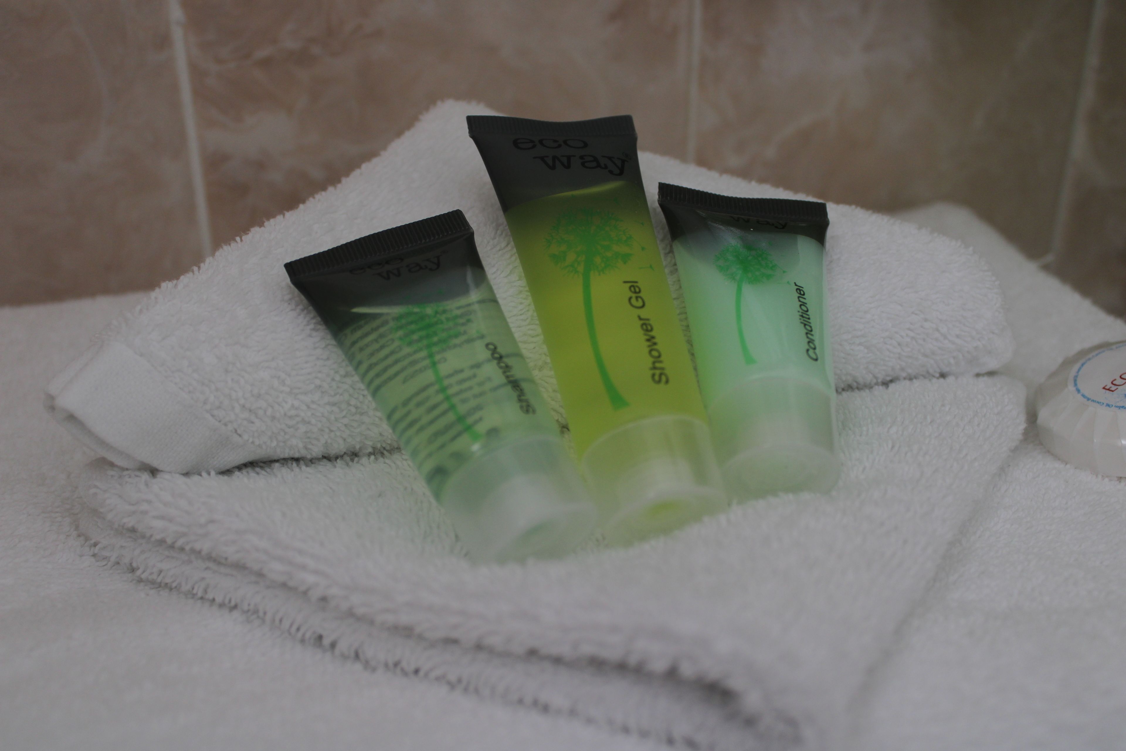 A white towel with three tubes of shower gel and a bottle of conditioner.