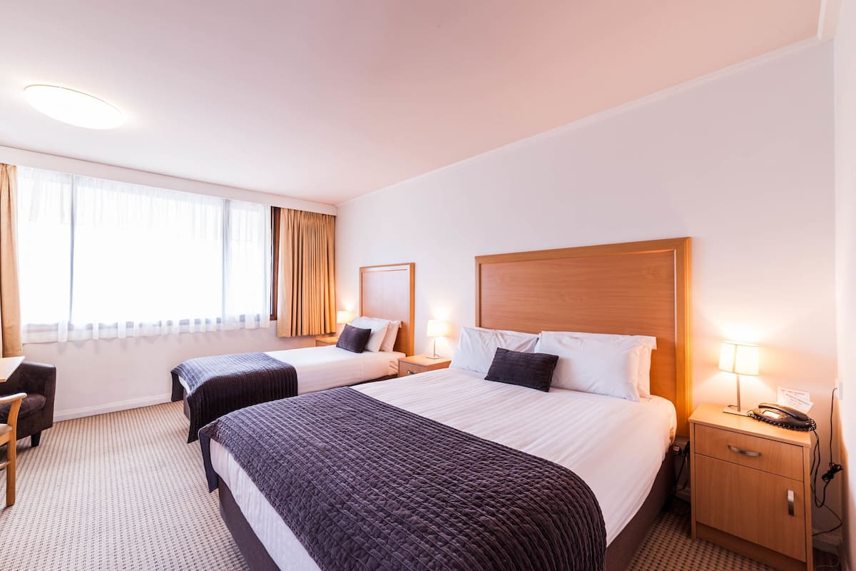 A hotel room with two beds, a desk, and a chair.