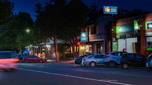 A motel with a signboard, a drive-thru, and parked cars.