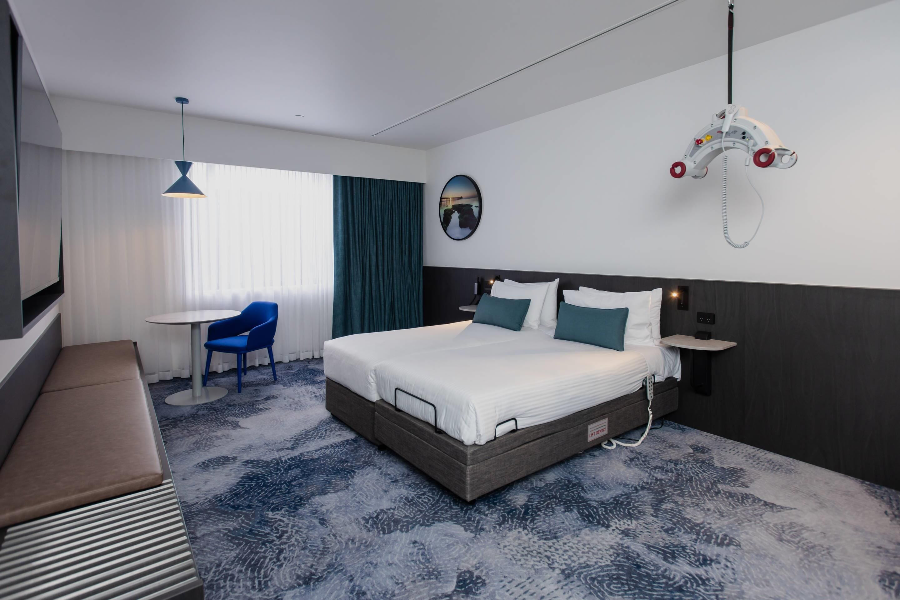 Hotelkamer met een groot bed, nachtkastje, stoel, bureau en een ophangmogelijkheid.