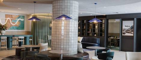 A modern lobby with a central column, seating areas, and a reception desk.