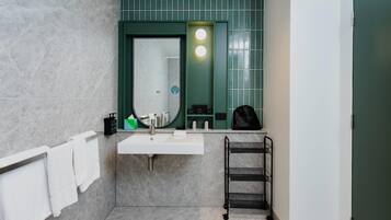 A bathroom with a white sink, green wall tiles, a towel rack, and a towel hanging on it.