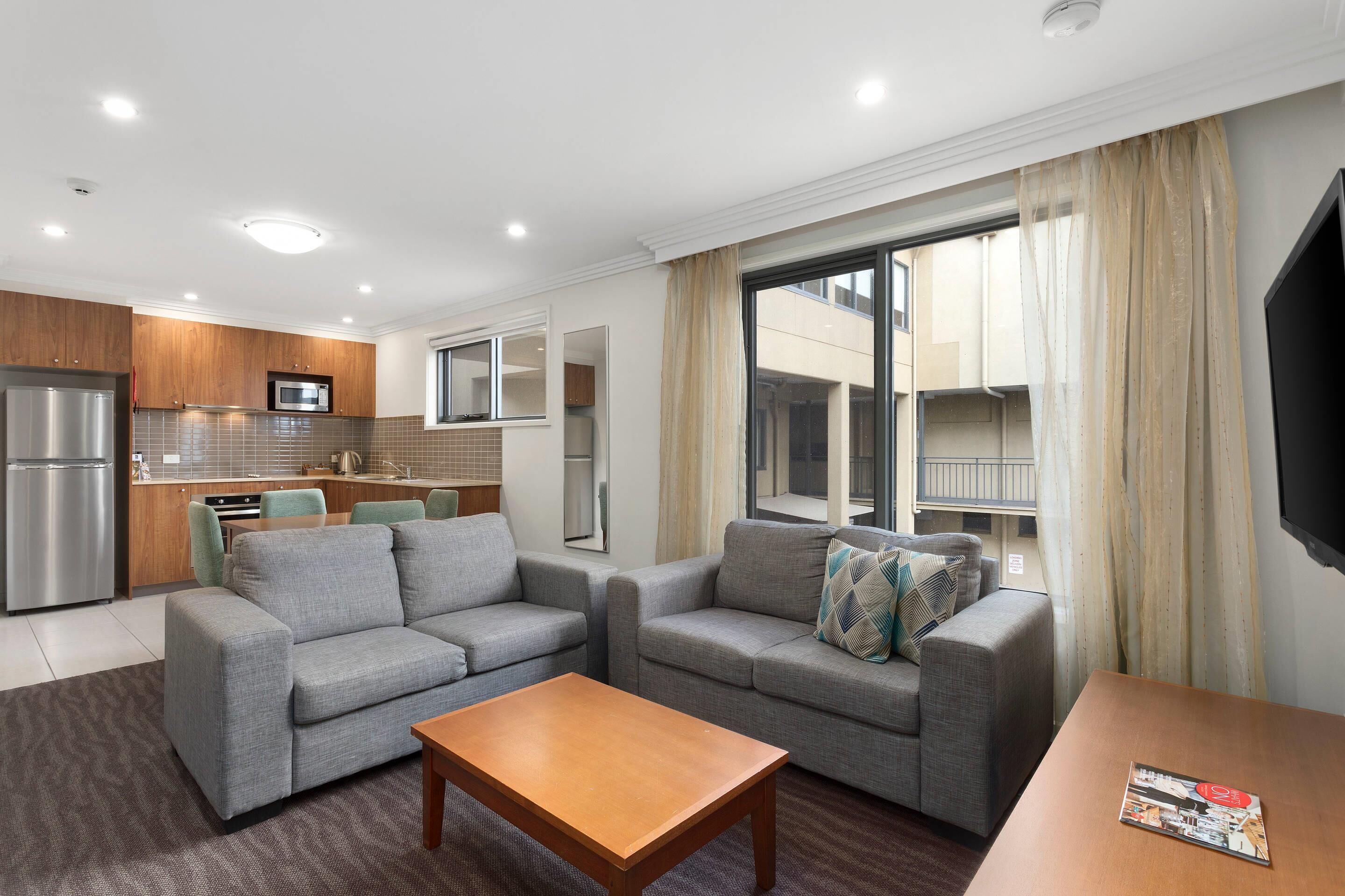 A modern living area with a sofa set, a wooden coffee table, and a TV on a stand.