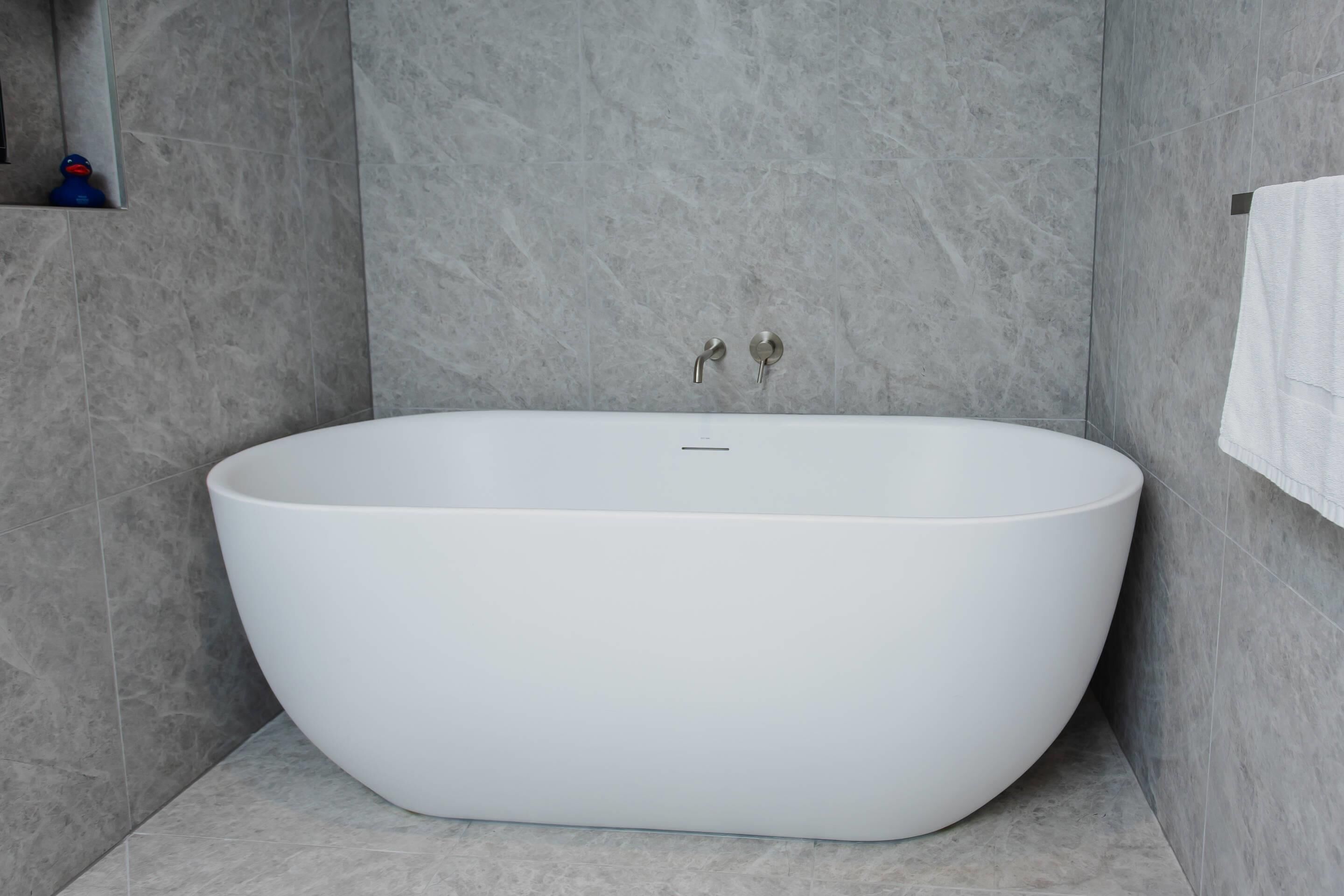 Un baño moderno con una bañera independiente, un perchero y un estante pequeño con objetos.