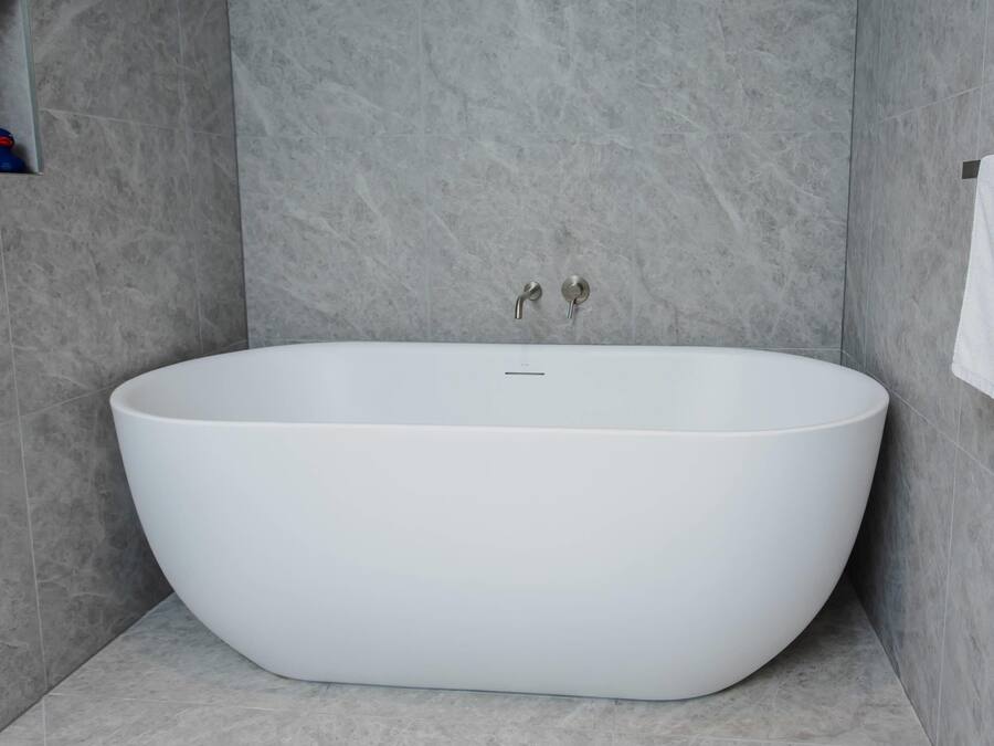 Un baño moderno con una bañera independiente, un perchero y un estante pequeño con objetos.