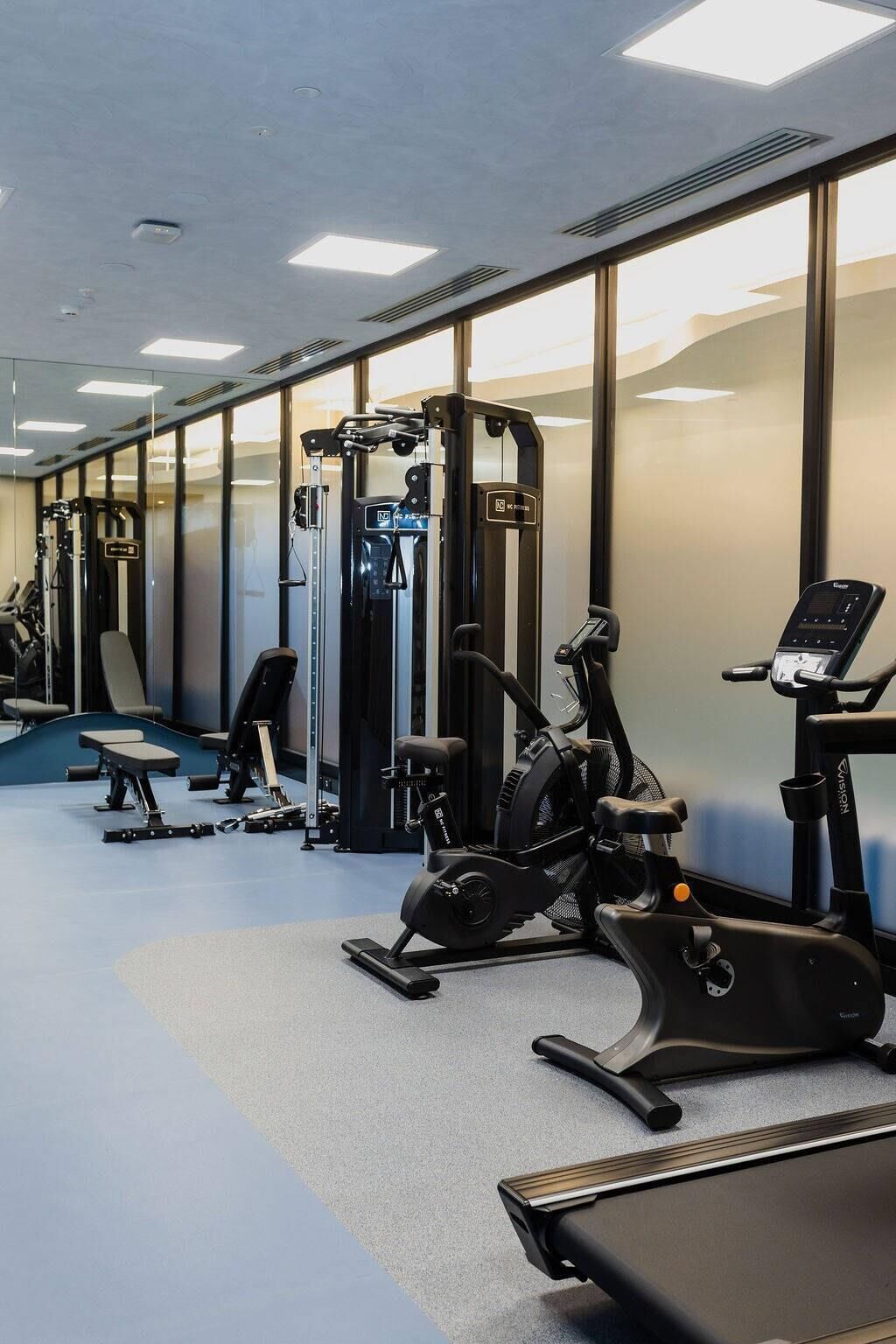 Une salle de sport équipée de matériel d’exercice, d’un tapis de course et d’un vélo d’appartement.