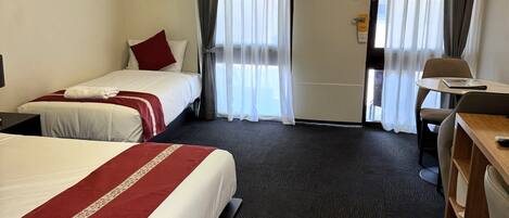 A hotel room with two beds, a desk, and a chair.