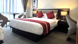 A hotel room with a bed, two bedside tables, a chair, a desk, a lamp, and a window with curtains. - Botanical Motel (Hamilton)