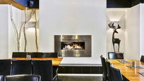 A modern dining area with a central fireplace, black leather chairs, and a wooden table. - Botanical Motel (Hamilton)
