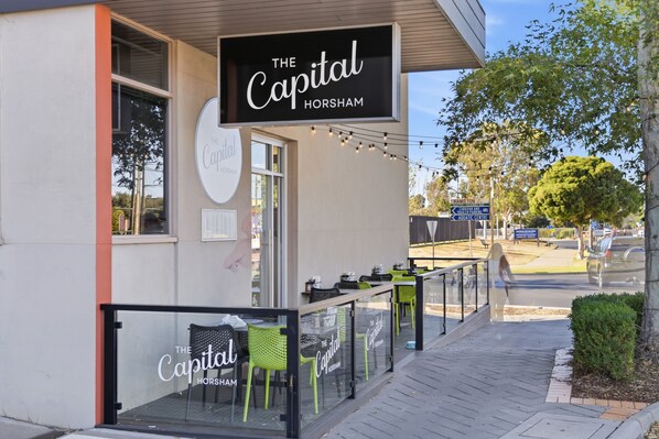 A restaurant named 'The Capital Horsham' with outdoor seating and a sign indicating nearby attractions. - The Capital Horsham (Horsham)