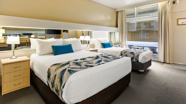 A hotel room with a large bed, bedside tables, a desk, and a view of the city. - Comfort Inn & Suites Lakes Entrance (Lakes Entrance)