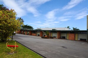 A building with a parking lot, a swing set, and a tree with pink flowers. - Comfort Inn & Suites Lakes Entrance (Lakes Entrance)