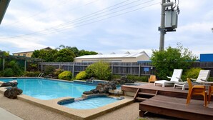 A backyard with a swimming pool, a wooden deck, and lounge chairs. - Comfort Inn & Suites Lakes Entrance (Lakes Entrance)