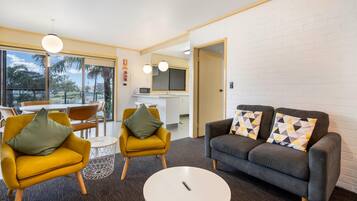 Una sala moderna con un sofá, dos sillones, una mesita de centro y un comedor con mesa y sillas.