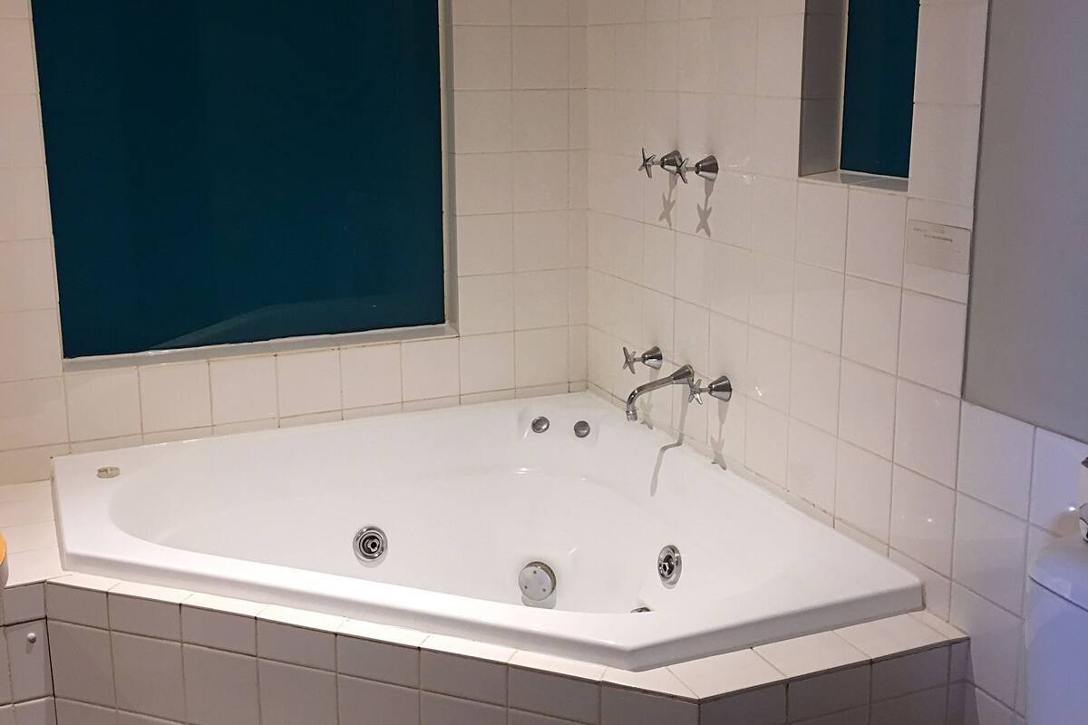 A modern bathroom with a large bathtub, a toilet, and a shower area.