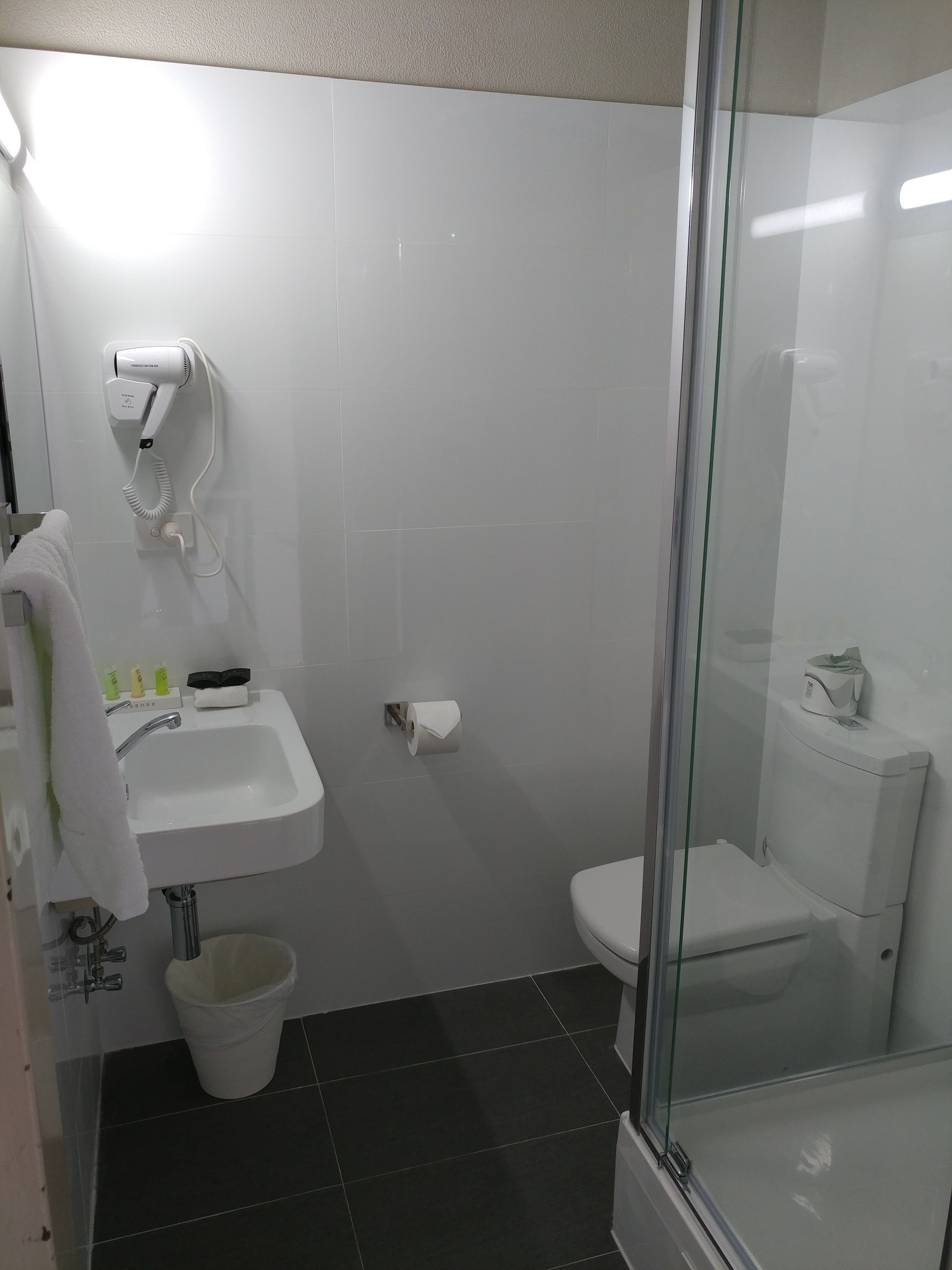 Un baño pequeño y moderno con un lavabo blanco, un inodoro y una ducha con mampara de vidrio.