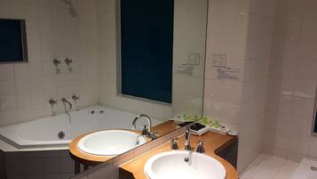Un baño moderno con lavamanos doble, una bañera grande y una ducha.