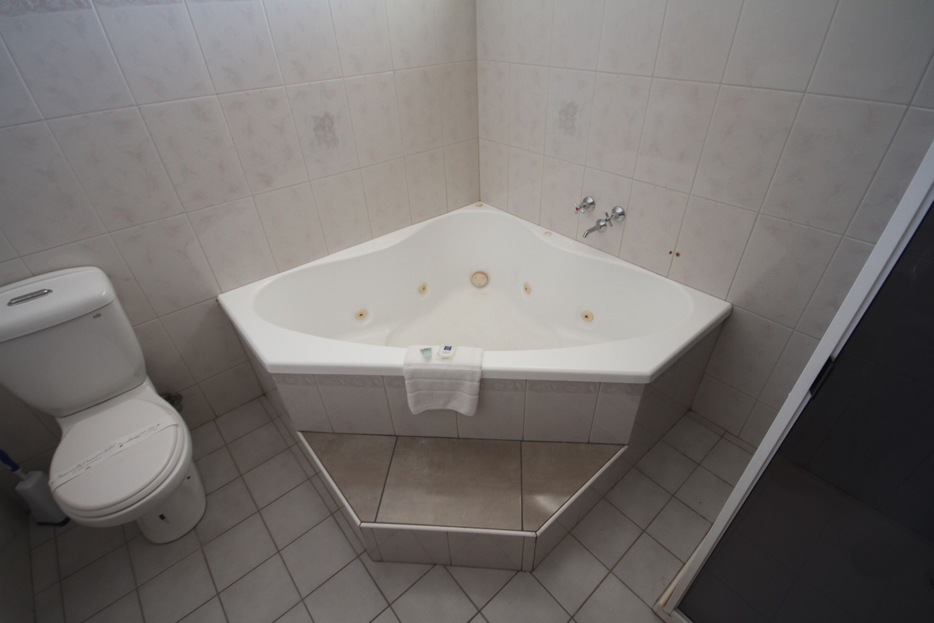 A bathroom with a white bathtub, a toilet, and a shower area.