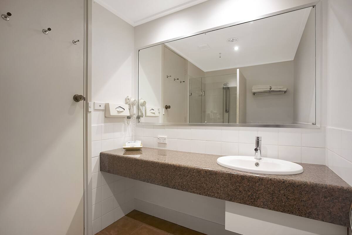 A bathroom with a granite countertop, white sink, and a large mirror.